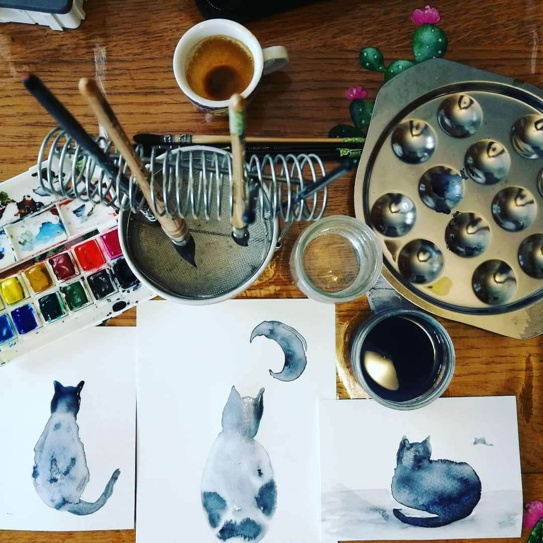 image d'un bureau sur lequel sont posées des aquarelles représentant des chats 